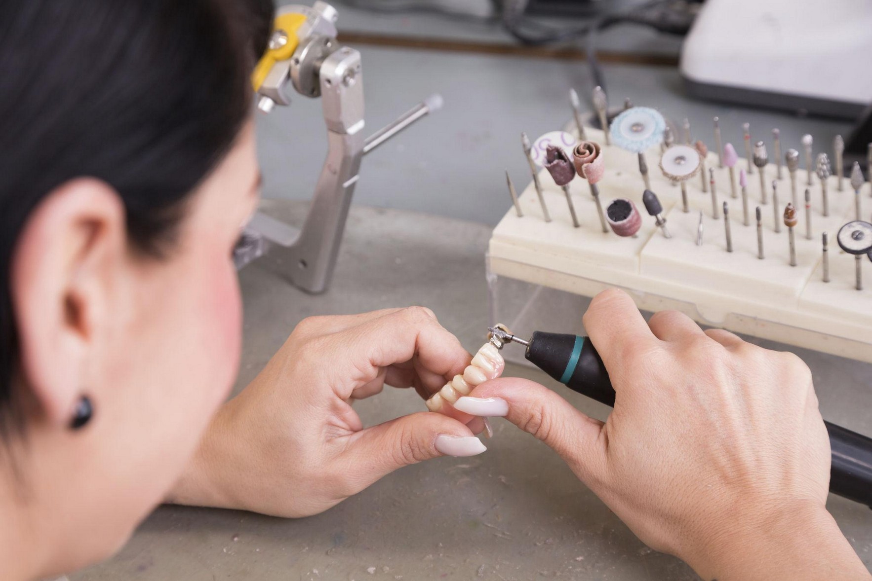 Dental laboratory technician finishing and polishing a final dental prosthesis in California.