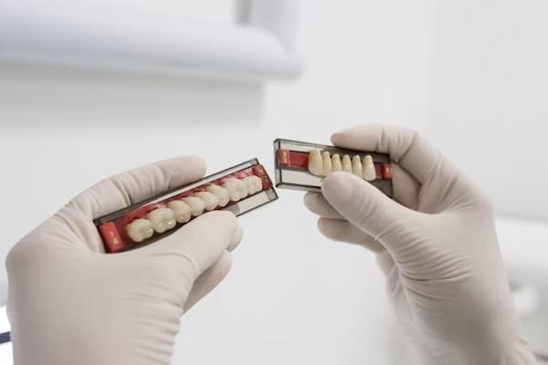 A dental technician looking at two sets of prosthetics at a full arch dental lab in California