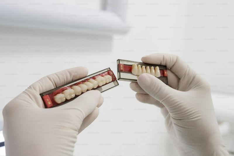 a pair of hands in gloves holding a box of teeth