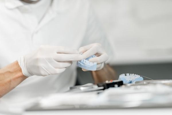 Dental laboratory technician using tools to shape a dental prosthetic in a dental prosthetic lab in California